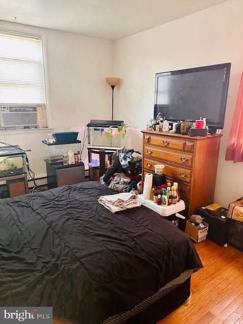 bedroom featuring cooling unit, light wood-type flooring, and a baseboard radiator