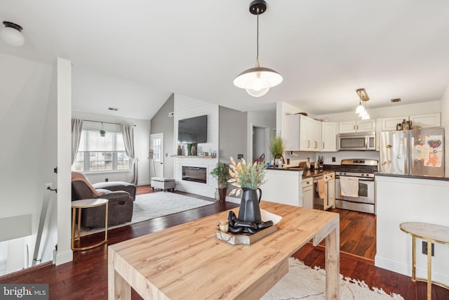 dining space with sink, dark wood-type flooring, and vaulted ceiling