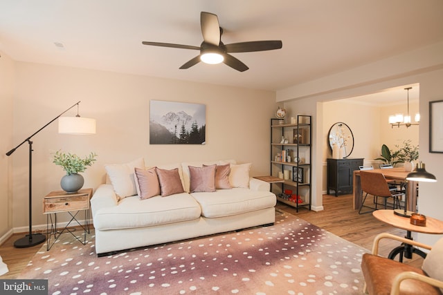 living room featuring ceiling fan with notable chandelier and light hardwood / wood-style flooring