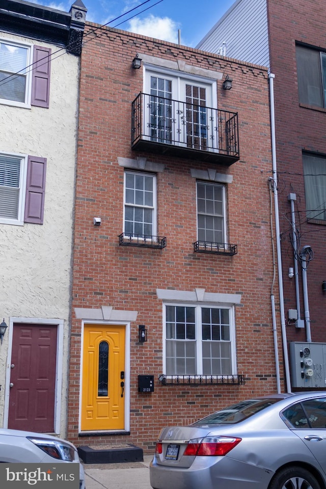 view of front facade with brick siding and a balcony