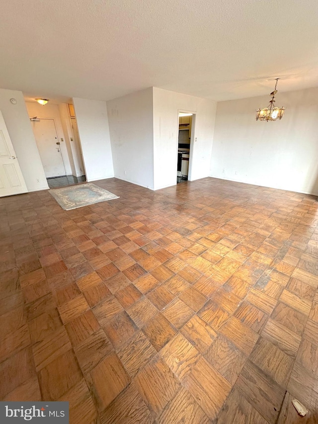 unfurnished living room with a textured ceiling, parquet flooring, and a chandelier