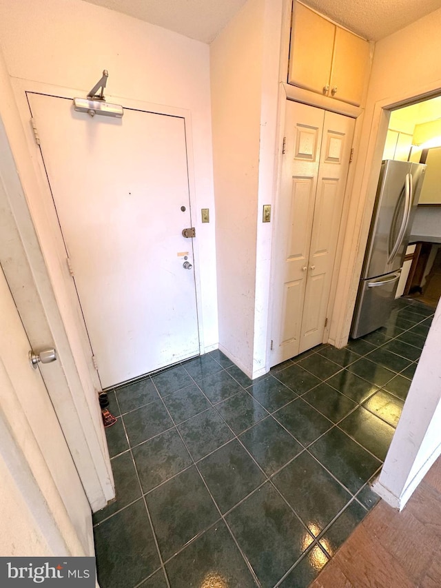 foyer featuring a textured ceiling and dark tile patterned floors