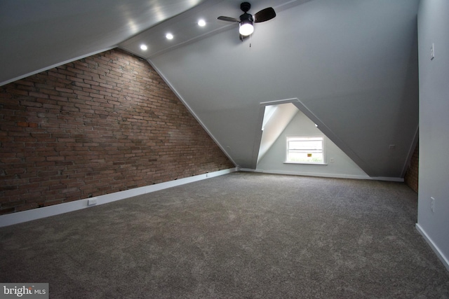 bonus room with dark carpet, ceiling fan, brick wall, and lofted ceiling