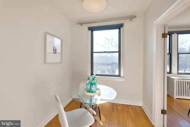 dining room featuring radiator, baseboards, and wood finished floors