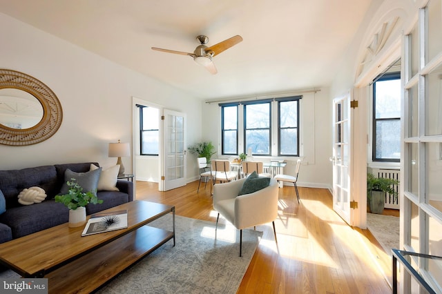 living area with radiator heating unit, baseboards, light wood-style flooring, and french doors