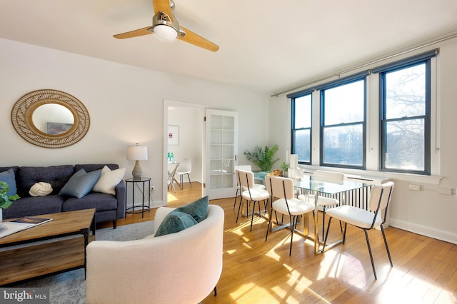 living room with plenty of natural light, wood-type flooring, baseboards, and ceiling fan