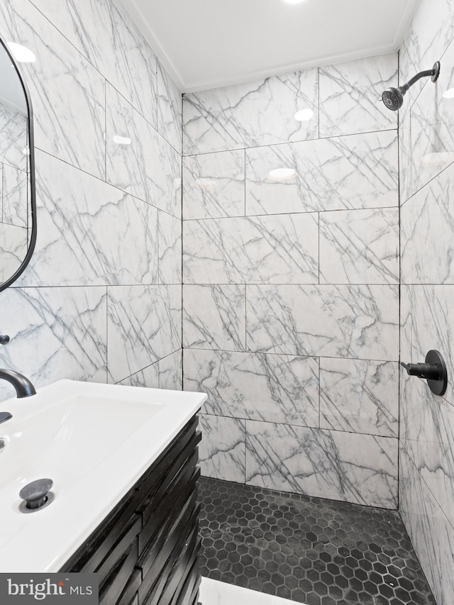 bathroom with crown molding, a tile shower, and vanity