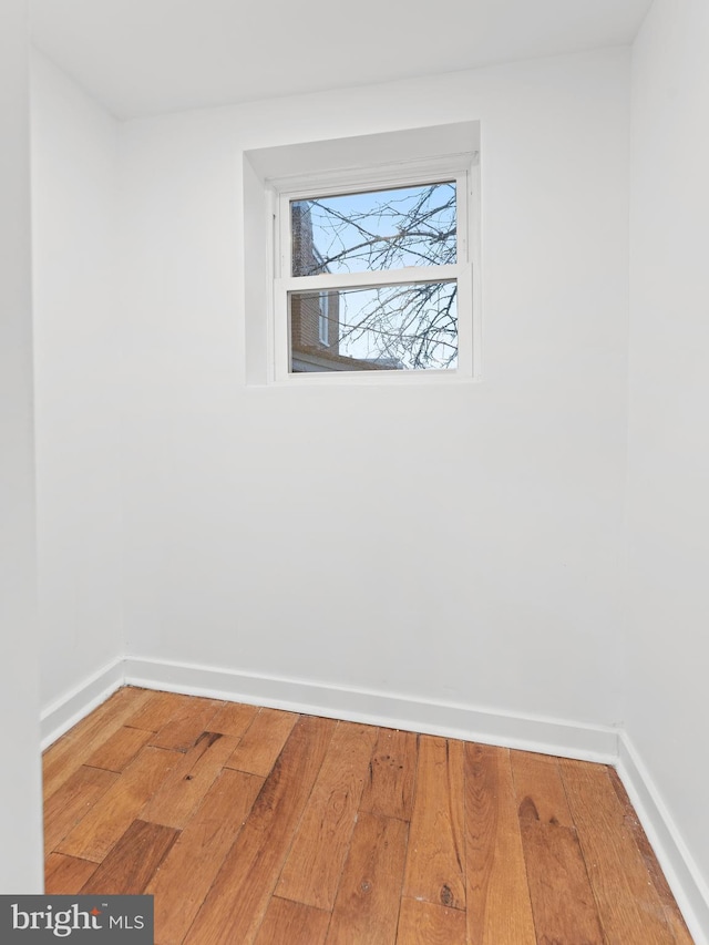 empty room with wood-type flooring and baseboards