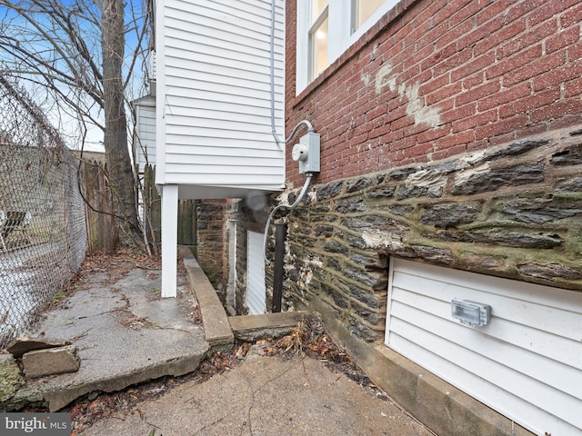 view of property exterior with brick siding and fence