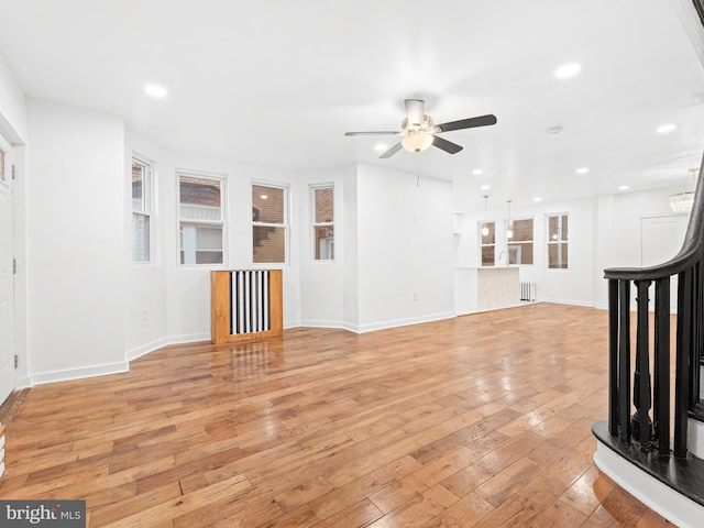 unfurnished living room featuring light wood finished floors, recessed lighting, ceiling fan, baseboards, and stairs