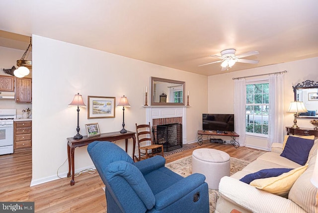 living room featuring a brick fireplace, light hardwood / wood-style floors, and ceiling fan