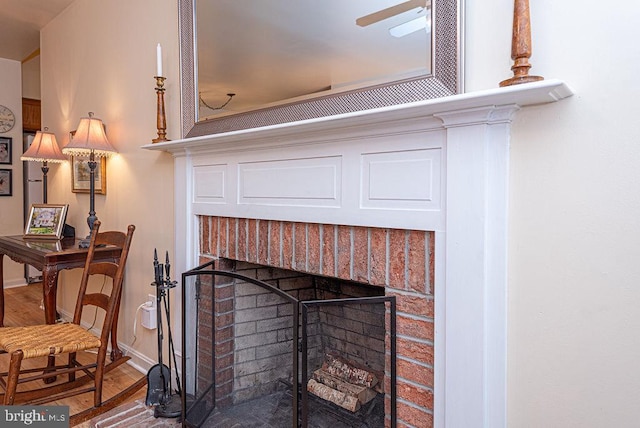 interior details with a brick fireplace, hardwood / wood-style flooring, and ceiling fan