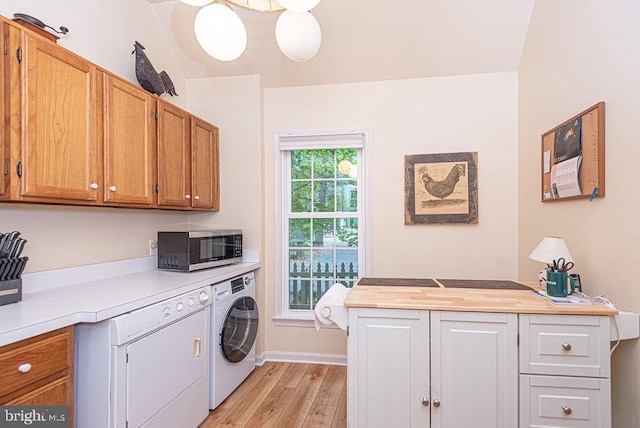 clothes washing area featuring cabinets, washer and dryer, and light wood-type flooring