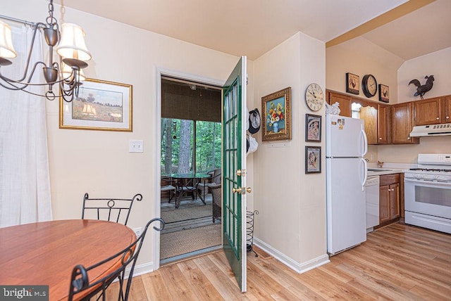 kitchen with white appliances, pendant lighting, an inviting chandelier, and light wood-type flooring