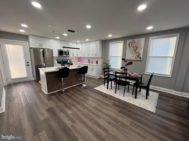 kitchen with white cabinetry, appliances with stainless steel finishes, hanging light fixtures, and a center island