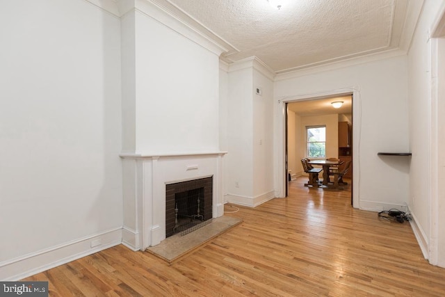 unfurnished living room featuring a fireplace, crown molding, a textured ceiling, and light hardwood / wood-style flooring