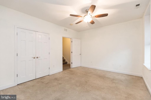 unfurnished bedroom with ceiling fan, a closet, and light colored carpet