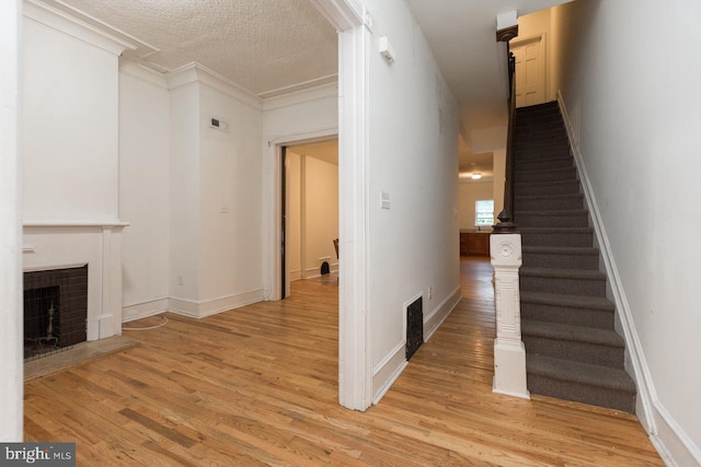 interior space featuring hardwood / wood-style flooring, ornamental molding, and a textured ceiling