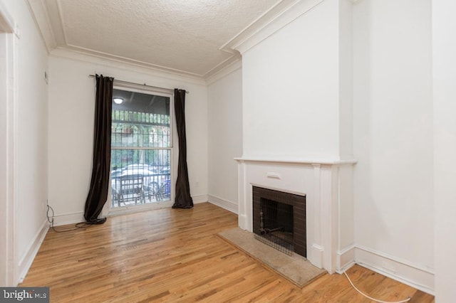 unfurnished living room with a brick fireplace, light hardwood / wood-style flooring, crown molding, and a textured ceiling