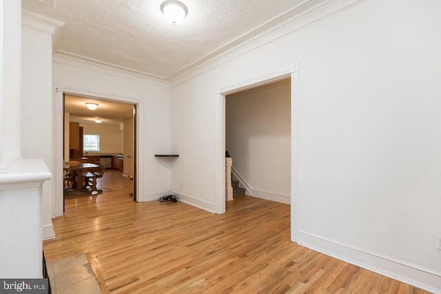 unfurnished room featuring light wood-type flooring, ornamental molding, and a textured ceiling