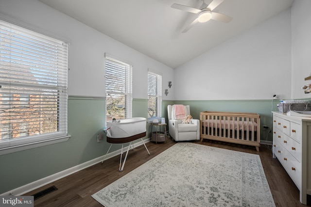 bedroom featuring dark wood-style floors, visible vents, baseboards, vaulted ceiling, and a nursery area