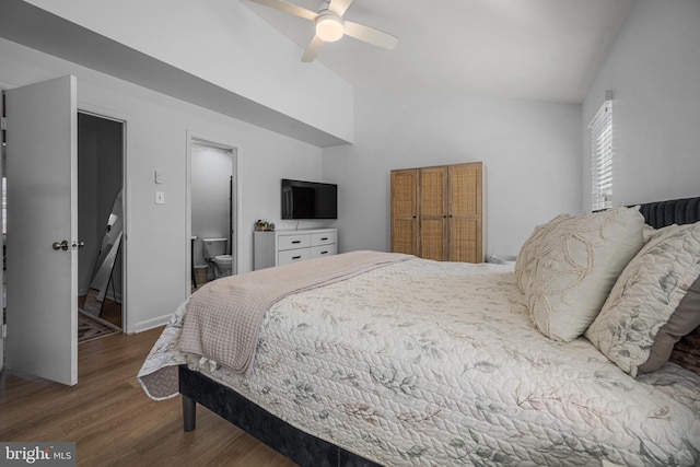 bedroom featuring lofted ceiling, ensuite bathroom, a ceiling fan, wood finished floors, and baseboards