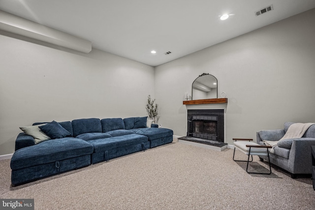 living room featuring a fireplace with raised hearth, carpet floors, visible vents, and recessed lighting