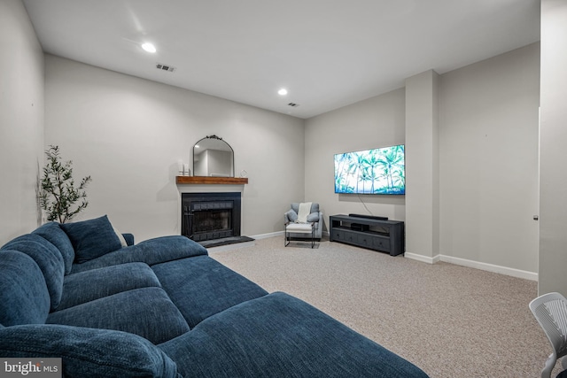 carpeted living room with baseboards, visible vents, a fireplace with raised hearth, and recessed lighting