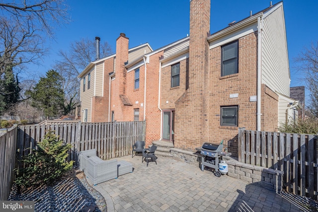 back of house featuring a patio area, brick siding, and a fenced backyard