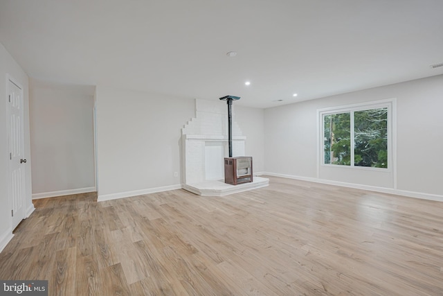 unfurnished living room with a wood stove and light wood-type flooring