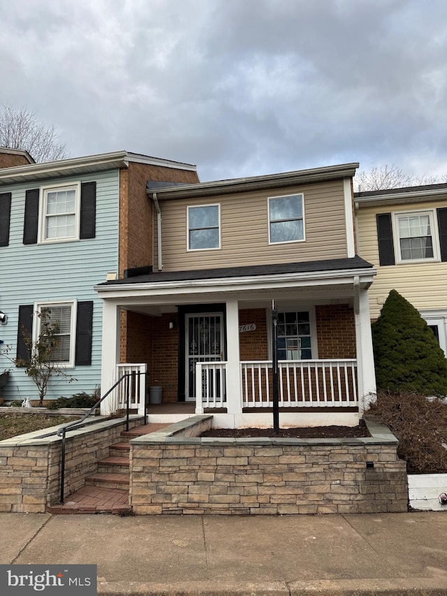 view of property with covered porch and brick siding