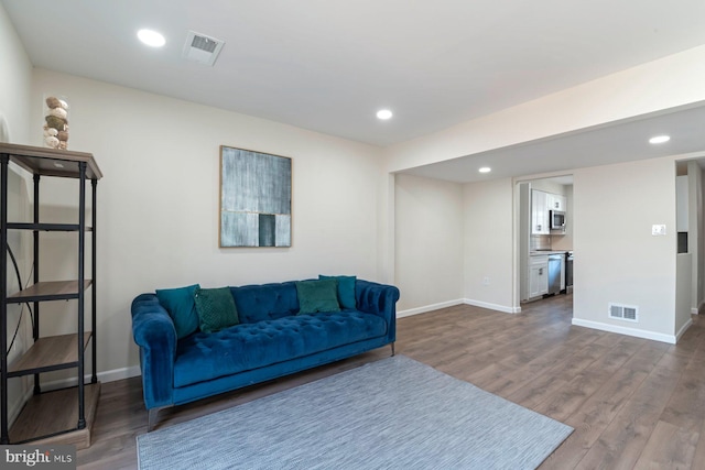 living room with baseboards, visible vents, dark wood-style flooring, and recessed lighting