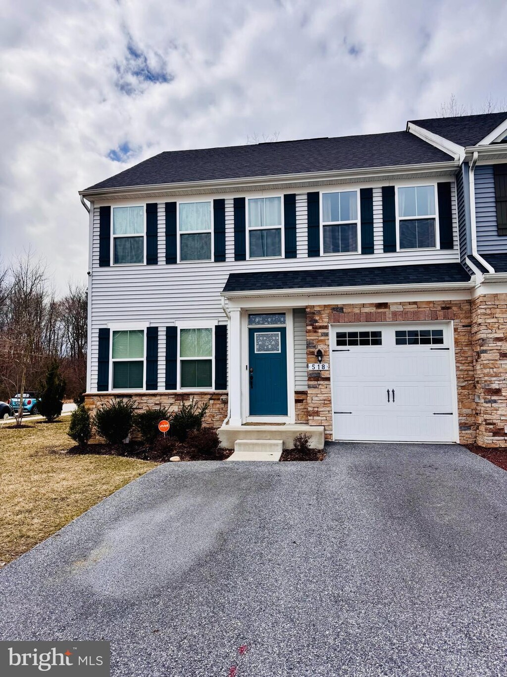view of front of house featuring an attached garage, aphalt driveway, and stone siding