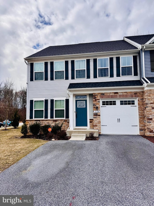 view of front of house with a garage, driveway, roof with shingles, and stone siding