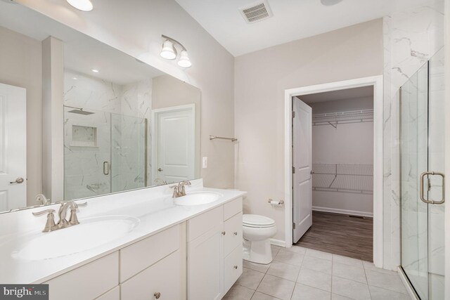 full bathroom with a marble finish shower, a spacious closet, a sink, and visible vents