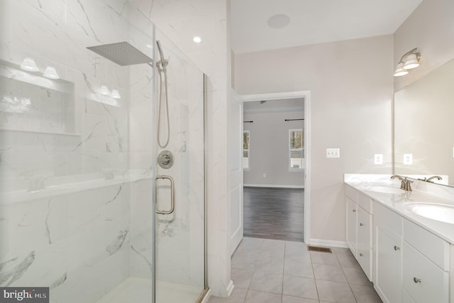 bathroom with double vanity, a marble finish shower, and a sink