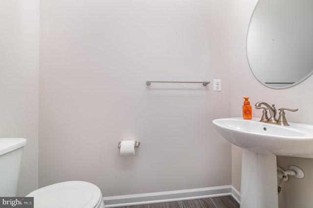 half bathroom featuring baseboards, toilet, and wood finished floors