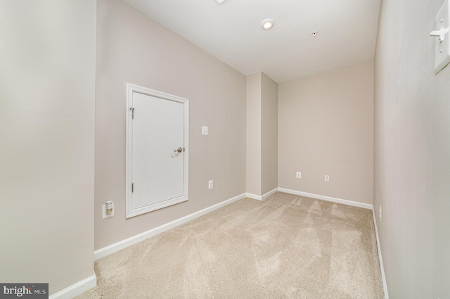 spare room featuring light colored carpet and baseboards