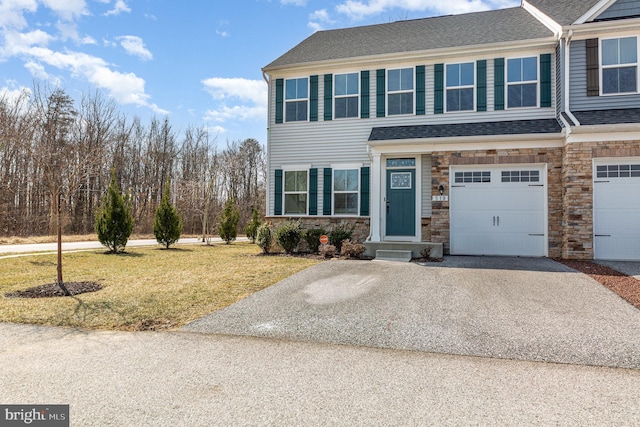 view of front of property featuring driveway, stone siding, roof with shingles, an attached garage, and a front yard