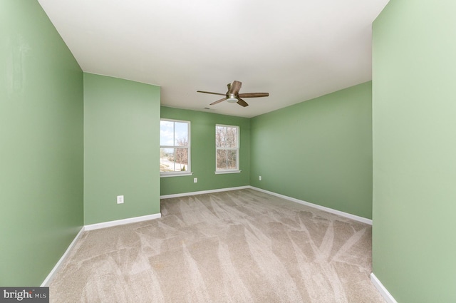 carpeted spare room featuring a ceiling fan and baseboards