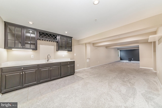 kitchen featuring recessed lighting, light countertops, glass insert cabinets, light carpet, and a sink