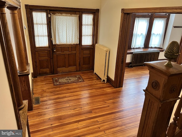 foyer featuring radiator, baseboards, visible vents, and hardwood / wood-style floors