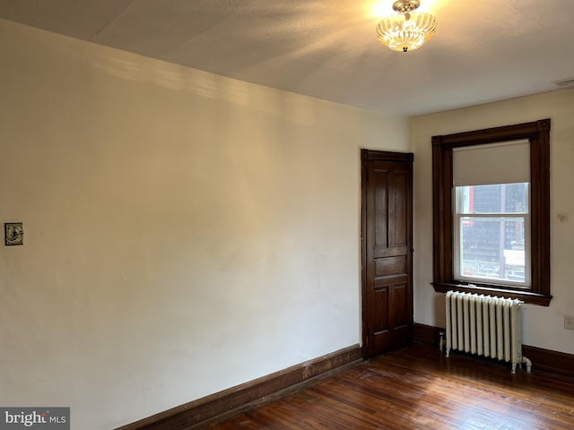 unfurnished room with radiator, baseboards, and dark wood finished floors