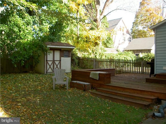 deck with an outbuilding, a shed, and a fenced backyard