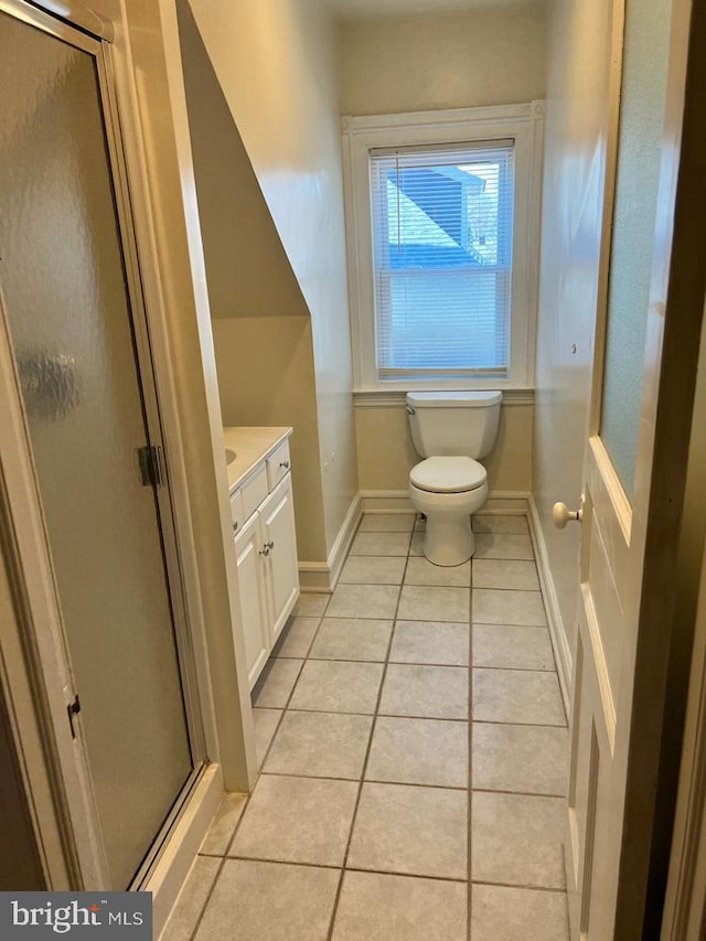 full bathroom featuring a stall shower, tile patterned flooring, vanity, and baseboards