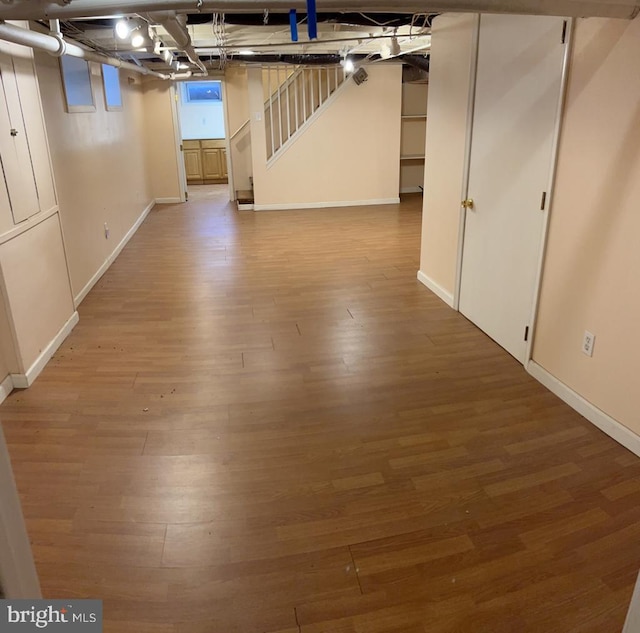 basement featuring baseboards, stairway, and wood finished floors