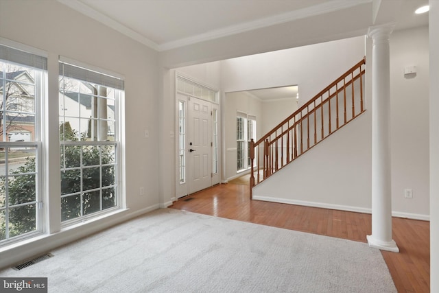 foyer entrance featuring crown molding, a wealth of natural light, and ornate columns