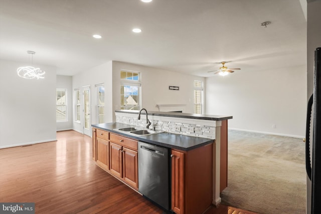 kitchen with dishwasher, pendant lighting, a fireplace, sink, and a kitchen island with sink