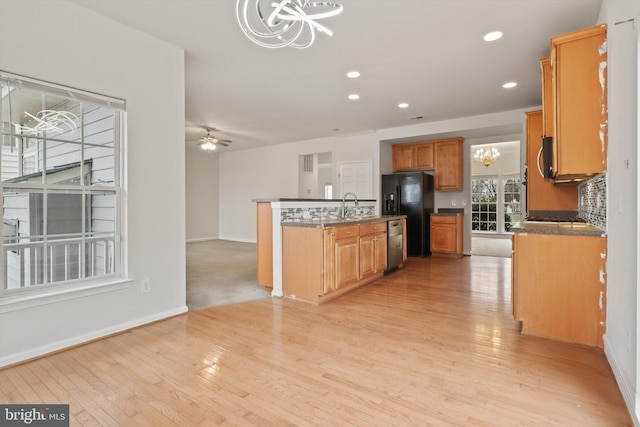 kitchen featuring stainless steel appliances, decorative light fixtures, light hardwood / wood-style floors, ceiling fan with notable chandelier, and sink