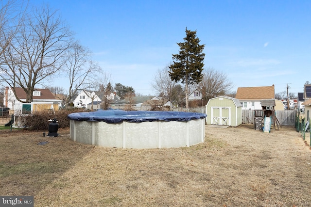 view of pool featuring a storage shed, a fenced in pool, a residential view, an outbuilding, and a playground